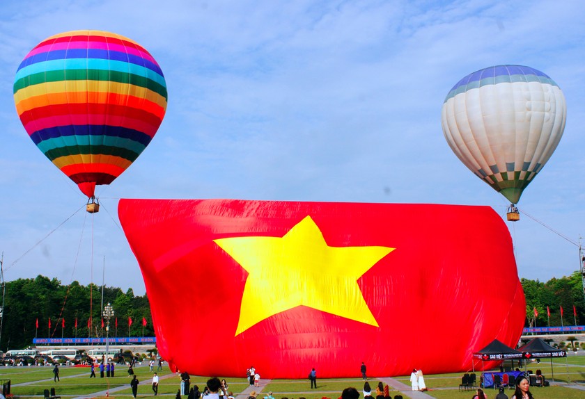 Đại kỳ Tổ quốc đang được 2 chiếc khinh kh&iacute; cầu k&eacute;o l&ecirc;n. Ảnh: Thi&ecirc;n &Yacute;