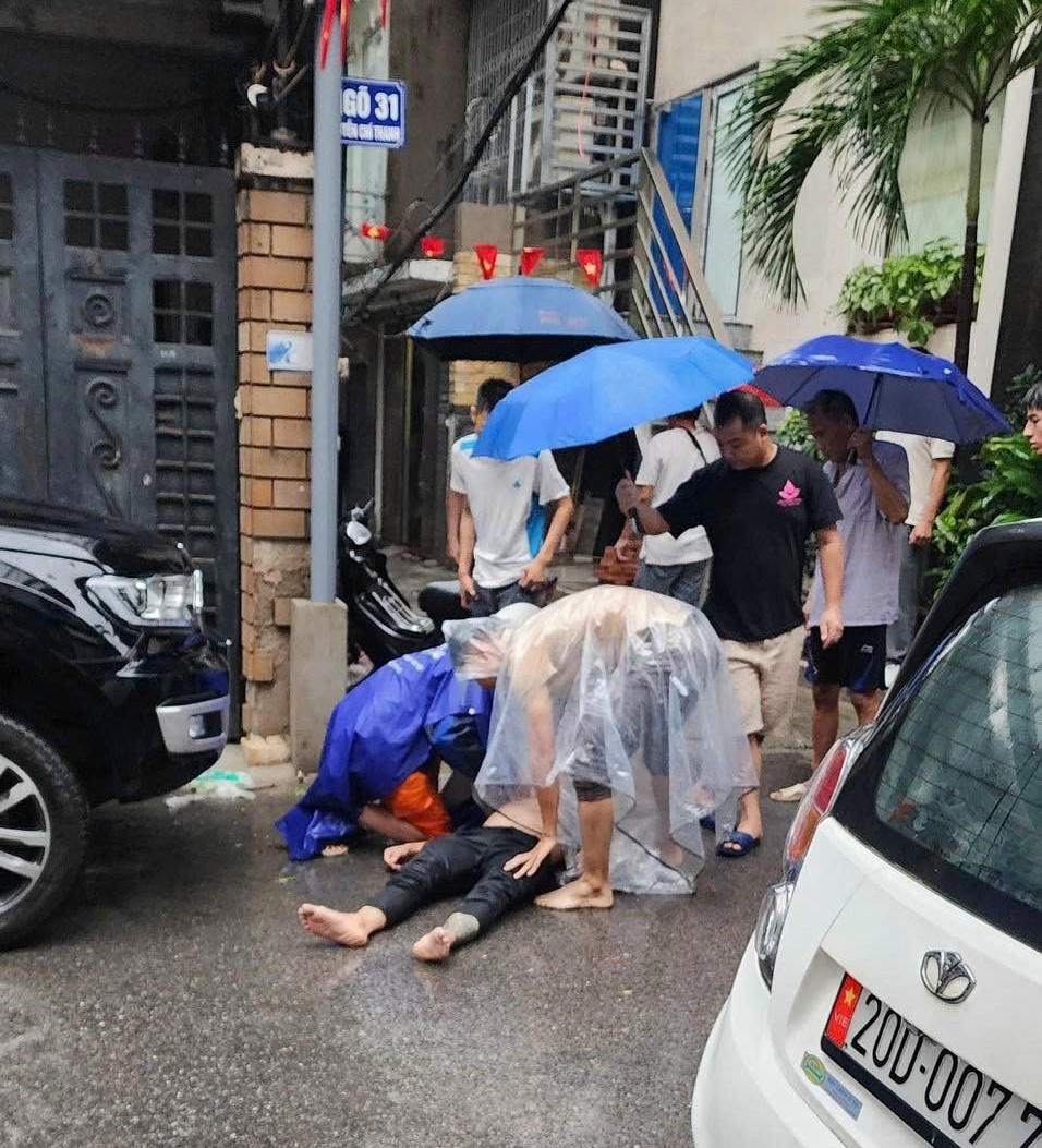 Một người đ&agrave;n &ocirc;ng nghi bị điện giật tại phố Nguyễn Ch&iacute; Thanh, phường Giảng V&otilde;, H&agrave; Nội đang được người d&acirc;n v&acirc;y xung quanh t&igrave;m c&aacute;ch đưa đi cấp cứu