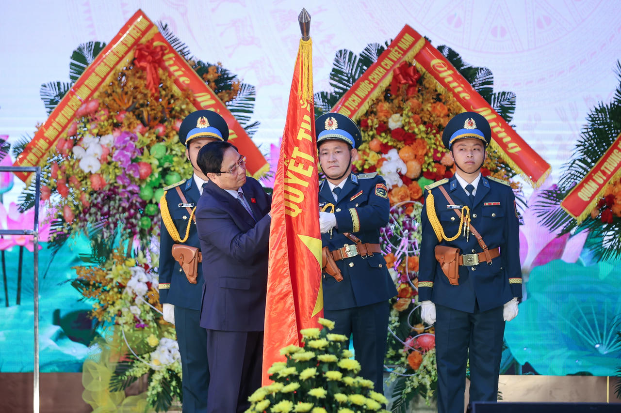Thủ tướng Phạm Minh Ch&iacute;nh gắn huy hiệu Danh hiệu Anh h&ugrave;ng lực lượng vũ trang nh&acirc;n d&acirc;n l&ecirc;n Qu&acirc;n kỳ Quyết thắng của Qu&acirc;n chủng Ph&ograve;ng kh&ocirc;ng - Kh&ocirc;ng qu&acirc;n - Ảnh: VGP/Nhật Bắc