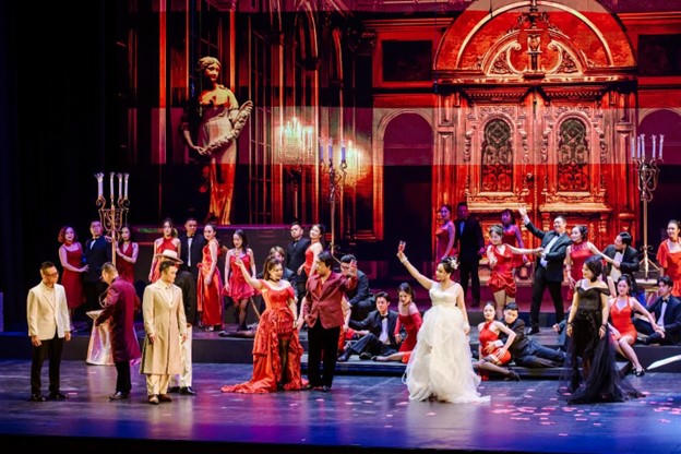 La Traviata - Đỉnh cao nghệ thuật opera và điều ít biết trong lần ra mắt đầu tiên Tiếng hợp xướng vang lên trong bản Libiamo ne’ lieti calici (Hãy cùng uống những ly rượu vui), khắc họa thế giới phù hoa của giới thượng lưu Paris.