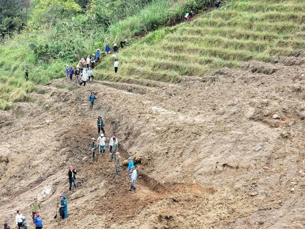 Lực lượng chức năng v&agrave; người d&acirc;n x&atilde; Ngọc Linh mở đường tạm băng qua điểm sạt lở để tiếp cận c&aacute;c th&ocirc;n đang bị c&ocirc; lập.