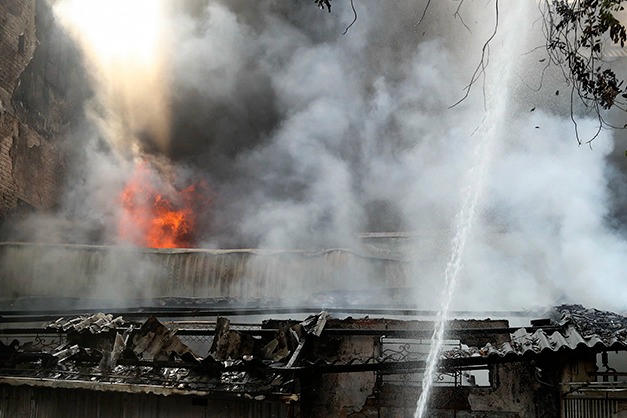Lực lượng PCCC phun nước trực diện v&agrave;o khu vực đang ch&aacute;y, kh&oacute;i trắng d&agrave;y đặc phủ k&iacute;n cả d&atilde;y nh&agrave;. (Ảnh: TTXVN).