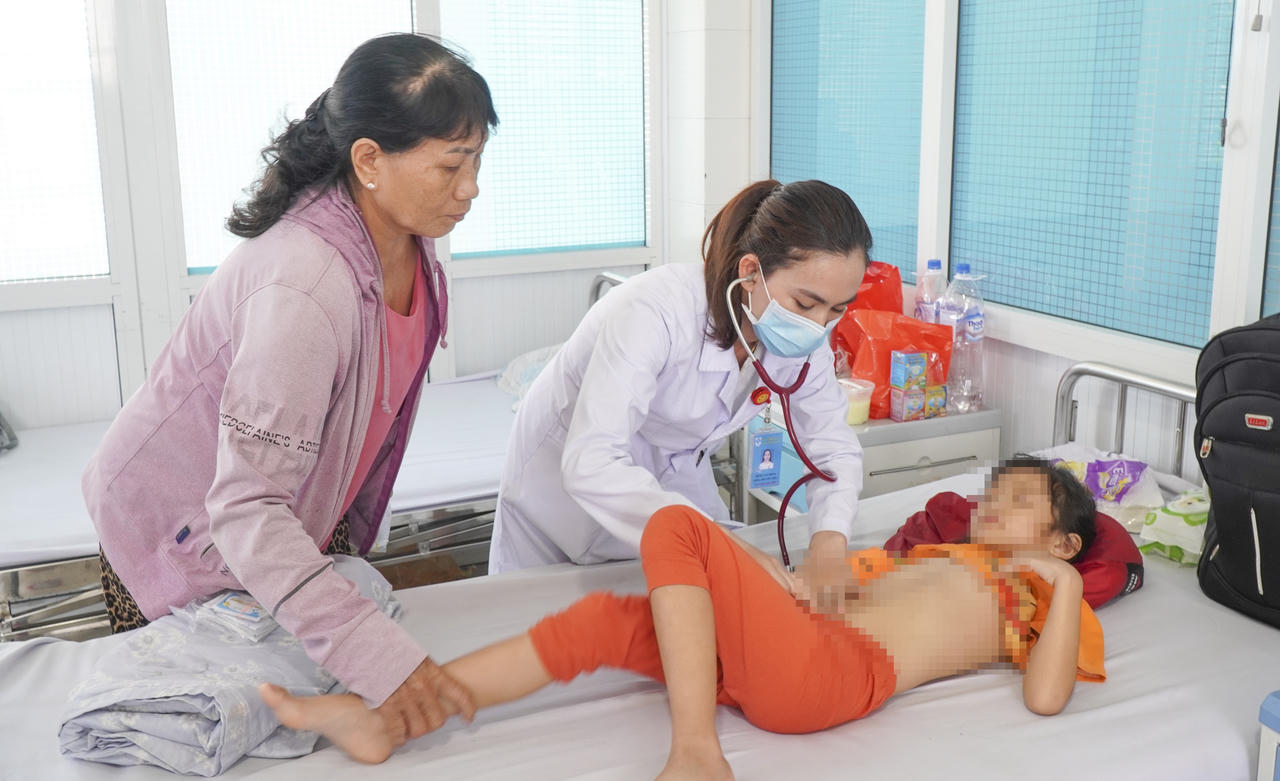 B&aacute;c sĩ kiểm tra sức khỏe cho bệnh nhi c&oacute; biểu hiện nghi ngộ độc thực phẩm sau khi ăn b&aacute;nh m&igrave;.