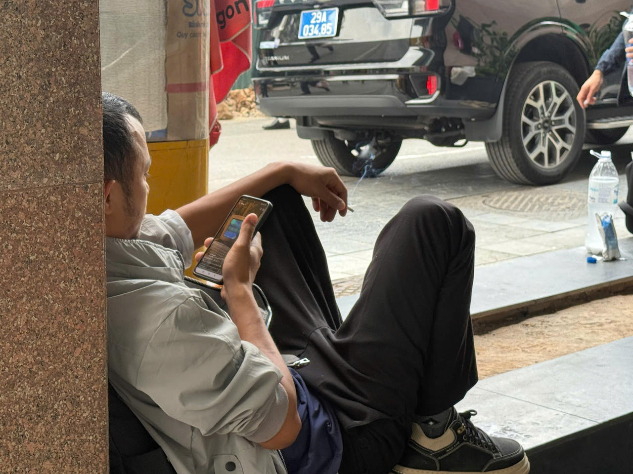 B&ecirc;n ngo&agrave;i khu kh&aacute;m bệnh bệnh viện Bạch Mai, một người đ&agrave;n &ocirc;ng trung tuổi vừa xem điện thoại, vừa h&uacute;t thuốc l&aacute;, c&aacute;ch đ&oacute; kh&ocirc;ng xa l&agrave; 'biển cẩm h&uacute;t thuốc l&aacute;'. (Ảnh: Thanh H&agrave;).