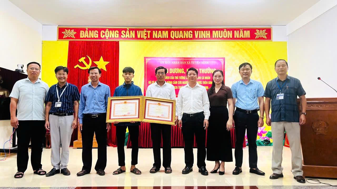 L&atilde;nh đạo Ban Thi đua - Khen thưởng tỉnh c&ugrave;ng l&atilde;nh đạo x&atilde; Tuy&ecirc;n B&igrave;nh chụp ảnh lưu niệm với hai cha con &ocirc;ng Cao Hữu T&igrave;nh sau lễ trao Bằng khen của Thủ tướng Ch&iacute;nh phủ v&igrave; h&agrave;nh động dũng cảm cứu người tr&ecirc;n s&ocirc;ng Gianh.