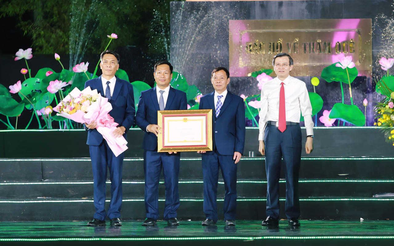 Gi&aacute;m đốc Học viện Ch&iacute;nh trị Quốc gia Đo&agrave;n Minh Huấn trao Hu&acirc;n chương Lao động hạng Nhất v&agrave; tặng hoa cho tập thể l&atilde;nh đạo Khu Di t&iacute;ch Quốc gia đặc biệt Kim Li&ecirc;n. Ảnh: Vũ Đồng