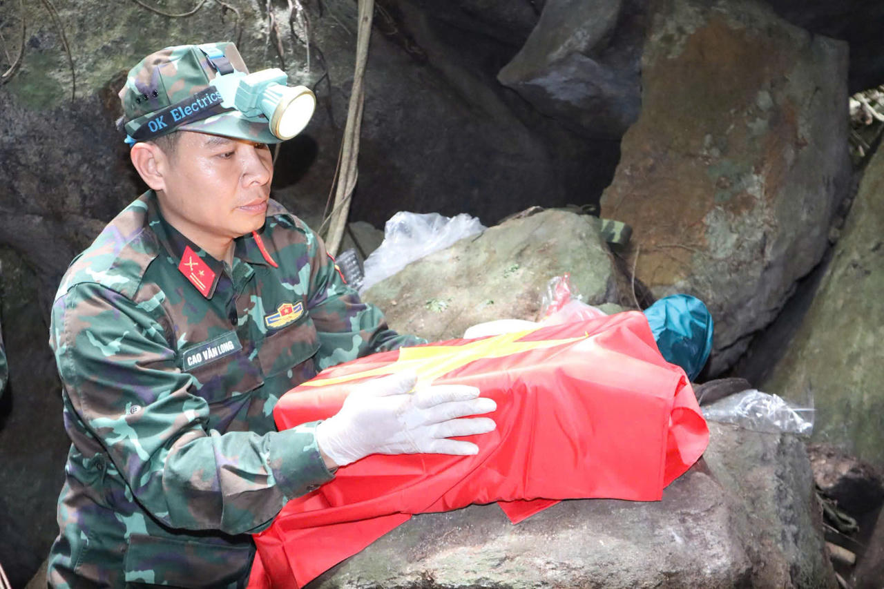 Trưa 13/7, bộ h&agrave;i cốt liệt sĩ đầu ti&ecirc;n được phủ cờ Tổ quốc để bộ đội đưa ra b&ecirc;n ngo&agrave;i. (Ảnh: V&acirc;n Anh)