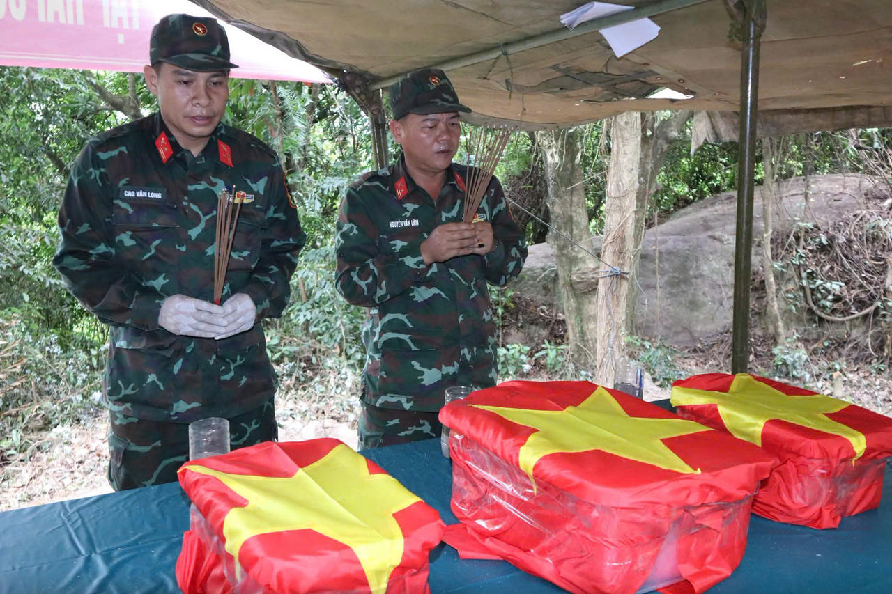 Ba bộ h&agrave;i cốt đầu ti&ecirc;n được đưa l&ecirc;n từ hang Đ&aacute; Sập ng&agrave;y 13/7, phủ cờ Tổ quốc v&agrave; đưa ra b&ecirc;n ngo&agrave;i để đ&aacute;nh số thứ tự. Lực lượng t&igrave;m kiếm đồng thời mở rộng t&igrave;m kiếm. (Ảnh: V&acirc;n Anh)