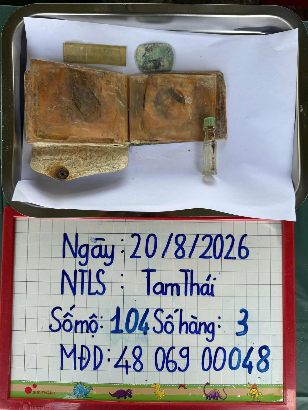 Lực lượng chức năng ph&aacute;t hiện tại phần mộ số 104 một chiếc v&iacute; c&oacute; ảnh ch&acirc;n dung phụ nữ, một bảng kim loại c&ograve;n nhận r&otilde; d&ograve;ng chữ &ldquo;TH&Agrave; HY SINH TẤT CẢ, QUYẾT KH&Ocirc;NG L&Agrave;M N&Ocirc; LỆ&rdquo;, chai dầu v&agrave; một số vật dụng c&aacute; nh&acirc;n kh&aacute;c.