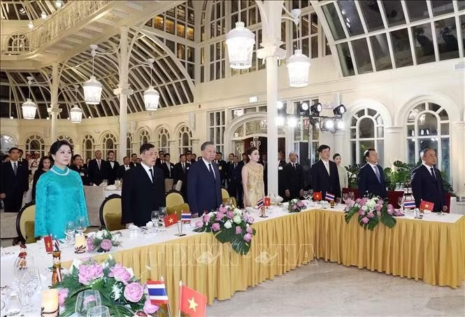 Tổng B&iacute; thư, Chủ tịch nước T&ocirc; L&acirc;m v&agrave; Phu nh&acirc;n Ng&ocirc; Phương Ly c&ugrave;ng Nh&agrave; vua Th&aacute;i Lan Maha Vajiralongkorn Phra Vajiraklaochaoyuhua v&agrave; Ho&agrave;ng hậu Suthida Bajrasudhabimalalakshana với c&aacute;c đại biểu thực hiện nghi thức ch&agrave;o cờ. Ảnh: Thống Nhất/TTXVN