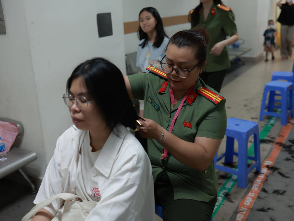 C&aacute;n bộ, chiến sĩ Ph&ograve;ng Tổ chức c&aacute;n bộ - CATP H&agrave; Nội trực tiếp đo, chải v&agrave; cắt t&oacute;c cho người d&acirc;n hiến tặng tại chương tr&igrave;nh. (Ảnh: CACC).